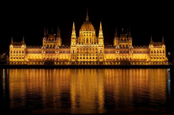 Illuminated view of the Hungarian Parliament Building reflecting in the Danube at night. Hungarian-Parliament Building-reflecting-in-the-Danube-at-night.