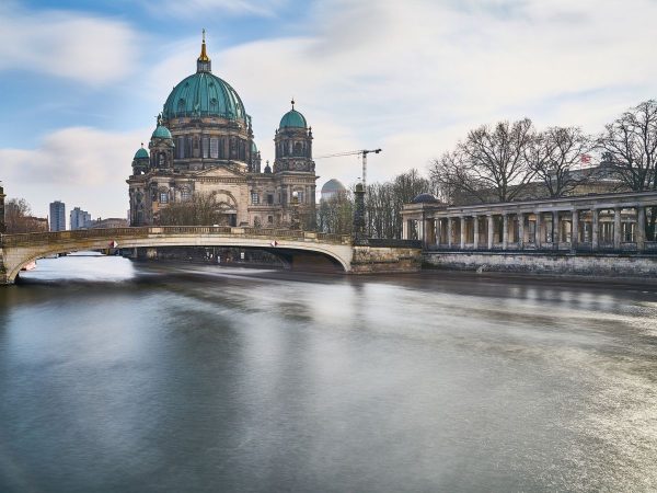 View of the iconic Berliner Dom (Berlin Cathedral) featuring its greenish turquoise domes alongside the Spree River Where to stay in Berlin. view of the iconic Berliner Dom (Berlin Cathedral) featuring its greenish turquoise domes alongside the Spree River