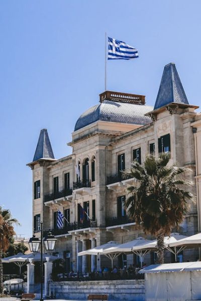 Stunning view of Poseidonion Grand Hotel with Greek flag in Spetses, Greece. Stunning view of Poseidonion Grand Hotel with Greek flag in Spetses, Greece.