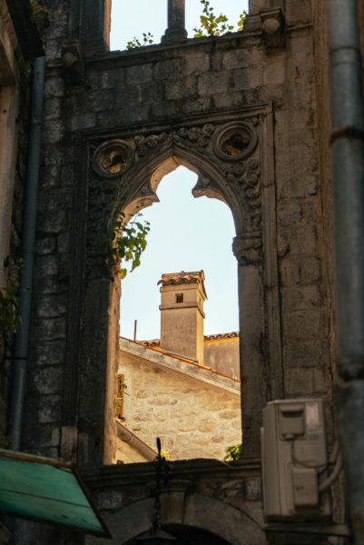 Gothic arch framing a stone rooftop in Dubrovnik, showcasing rich historical architecture. Gothic arch framing a stone rooftop in Dubrovnik, showcasing rich historical architecture.