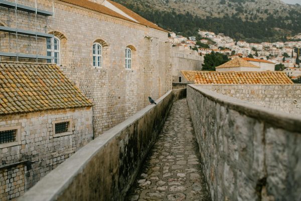 A scenic view of the ancient stone walls in Dubrovnik with a narrow cobblestone walkway, Dubrovnik, Croatia A scenic view of the ancient stone walls in Dubrovnik with a narrow cobblestone walkway, Dubrovnik, Croatia