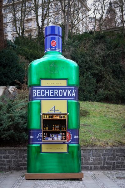 pexels-photo-15235099-15235099 Outdoor kiosk shaped like a giant Becherovka bottle displaying liquor in a retail setting.