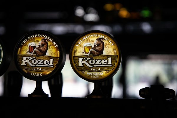 pexels-photo-17299767-17299767 Close-up of Kozel beer tap handles showcasing premium lager and dark beer branding in a cozy bar setting.