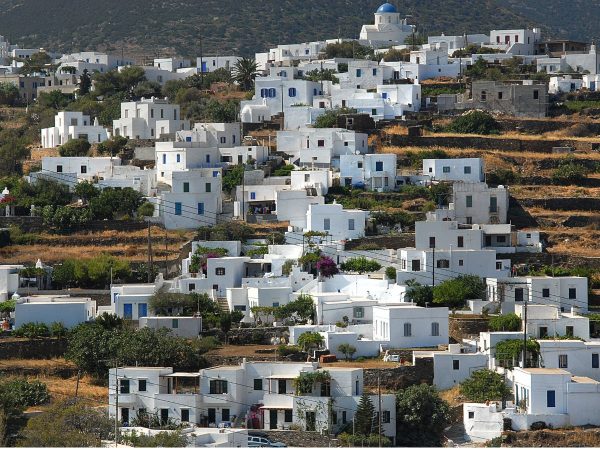 The White Washed Village of Apollonia , Sifnos, Greece A hillside village with white cubic houses and blue shutters under a clear sky. A church with a blue dome is perched at the top, evoking a serene Mediterranean feel.