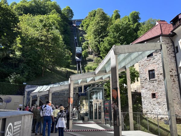 Funicular leading up to Ljubljana Castle. There are stone building in the courtyard with lots of bikes and tourists.
