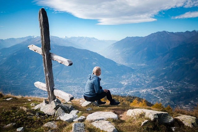 Women sitting on the top of the mountain looking out. Signpost in the foreground.